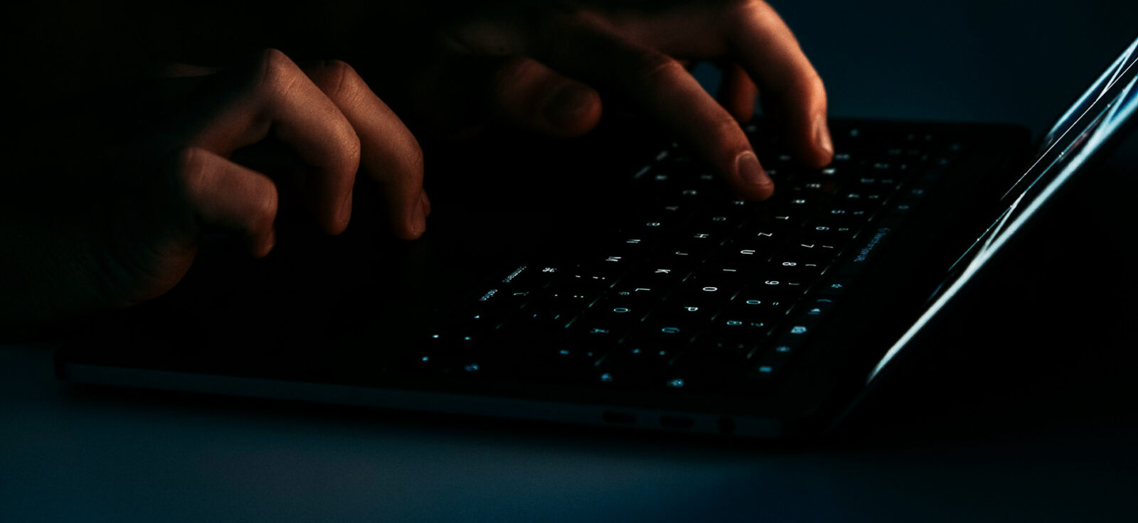photo rapproché de mains tapant sur un clavier sombre