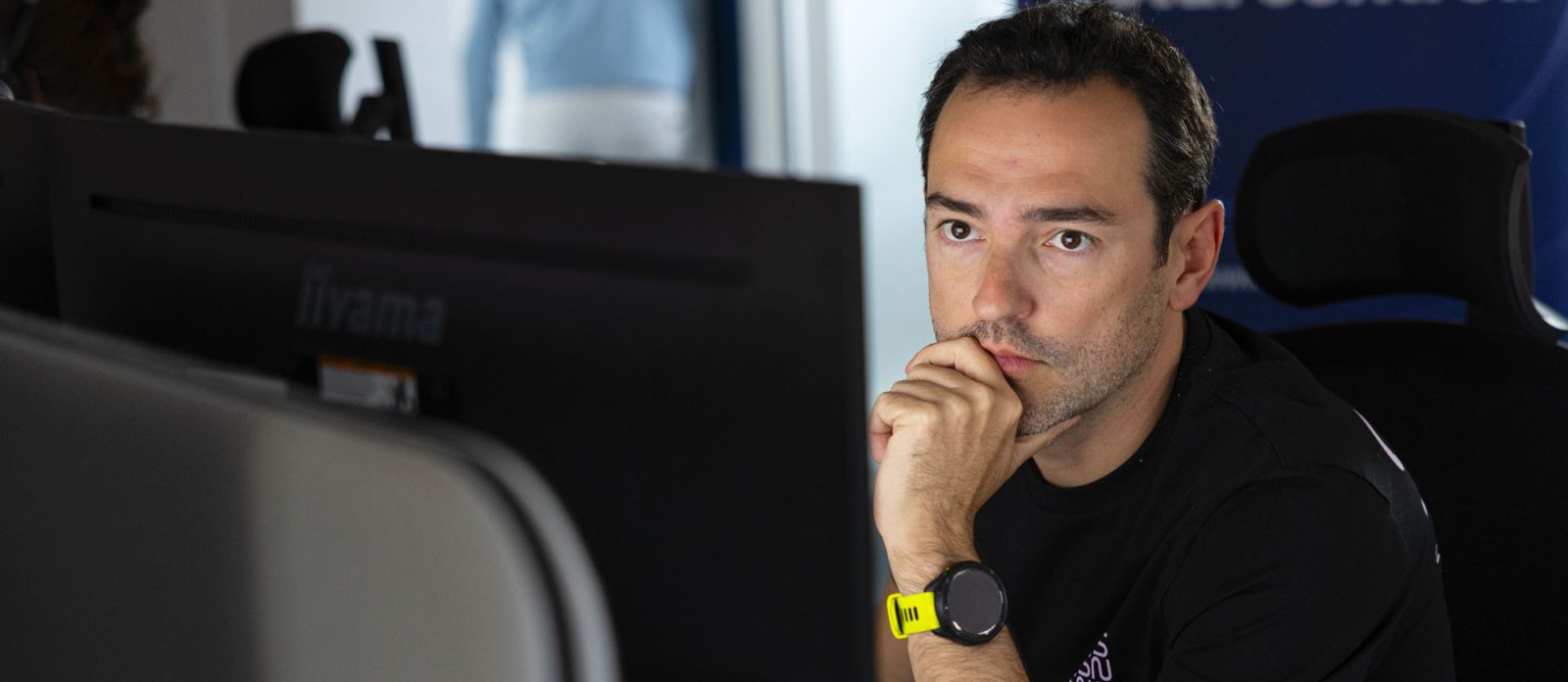 analyste SOC portant un t-shirt noir sns concentré sur son écran