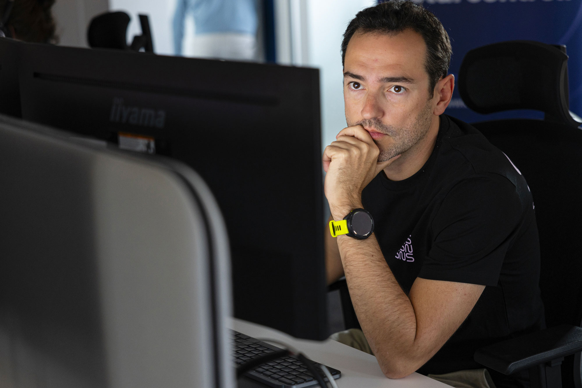 analyste SOC portant un t-shirt noir sns concentré sur son écran