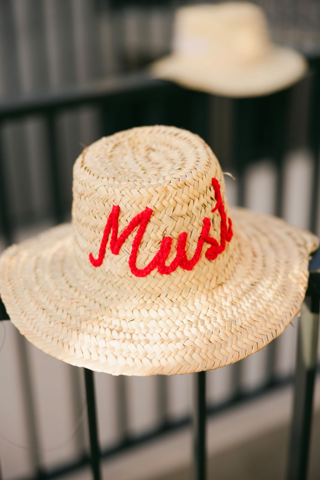 un châpeau de paille portant la mention Must brodée de fil rouge