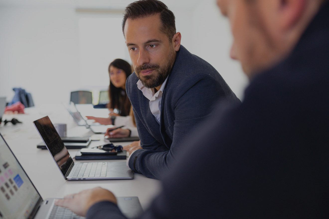 ingénieur commercial en costume assis à une table de réunion regardant l'écran de son collègue